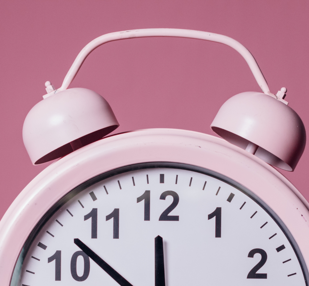 Close-up of a pink twin-bell alarm clock.