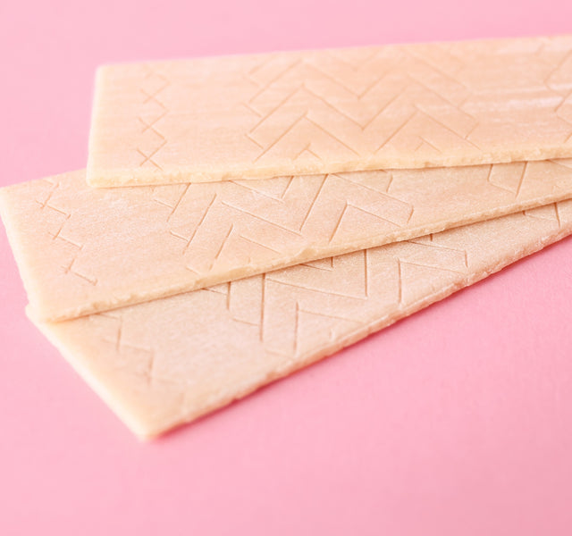 Three sticks of chewing gum on a pink background.