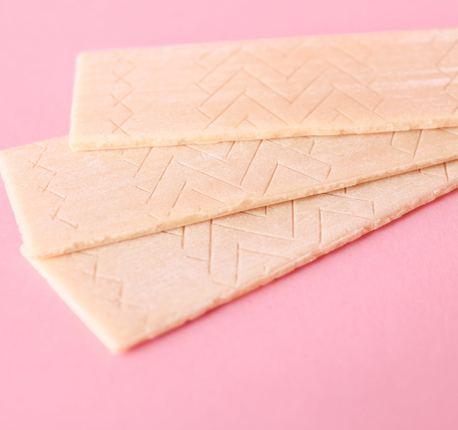 Three sticks of chewing gum on a pink background.