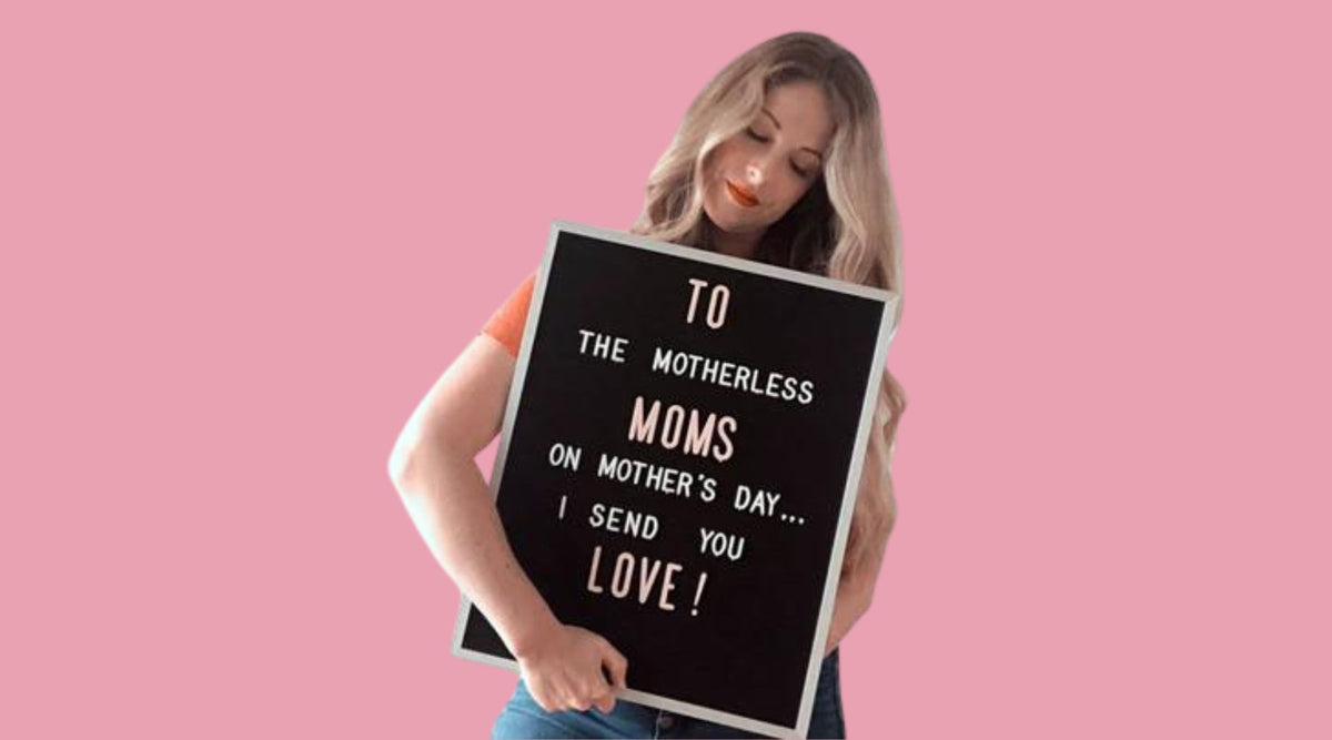 Woman holding a letter board with a Mother’s Day message for motherless moms.