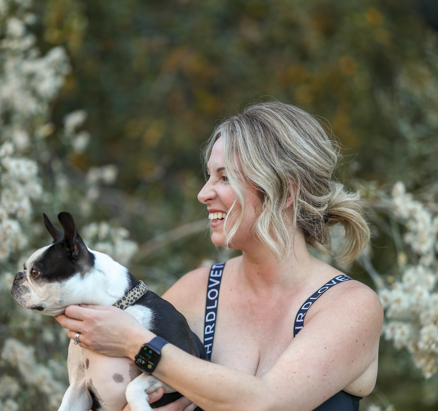 Sarah Komers holding a small black-and-white dog outdoors.