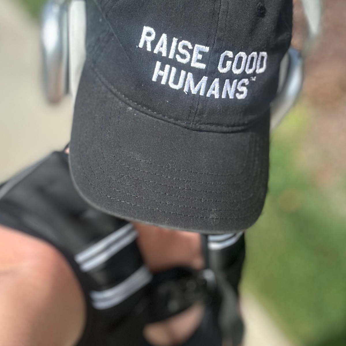 Close-up of a dark “Raise Good Humans” cap worn with a weighted vest.