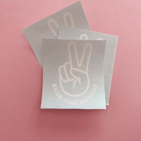 White peace-sign hand and “Raise Good Humans” car decals on backing sheets.