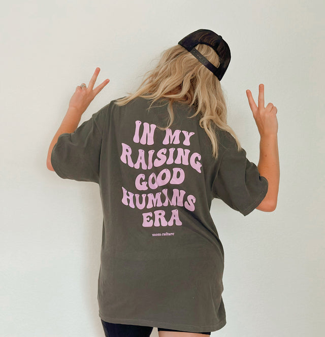 Back of a pepper gray T-shirt with pink “In My Raising Good Humans Era” lettering.