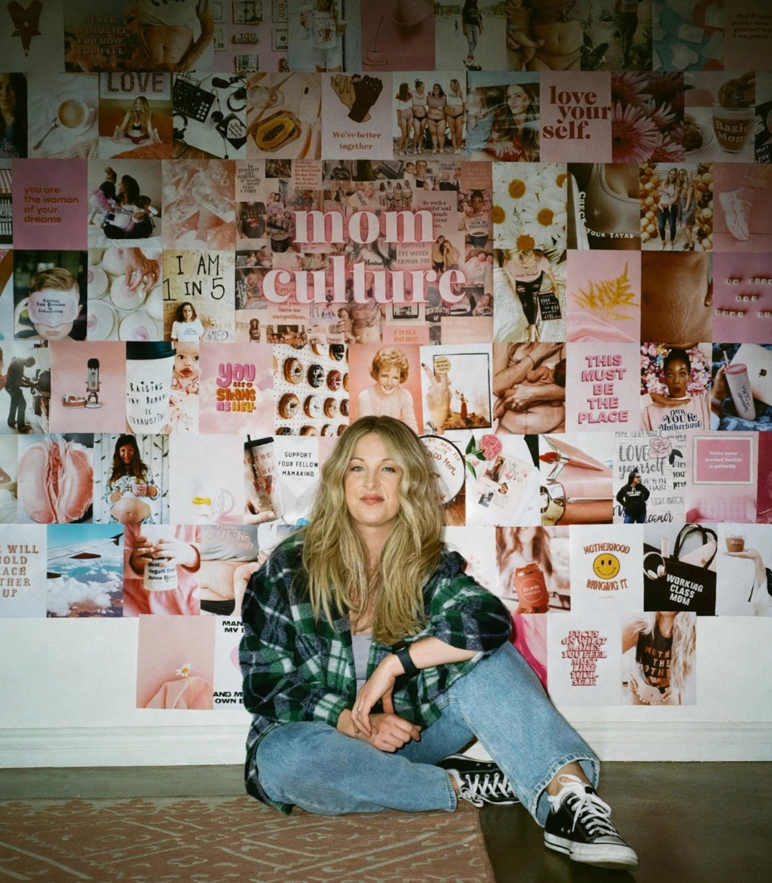 Mom Culture founder Sarah Komers seated in front of a collage of the brand’s motherhood imagery.