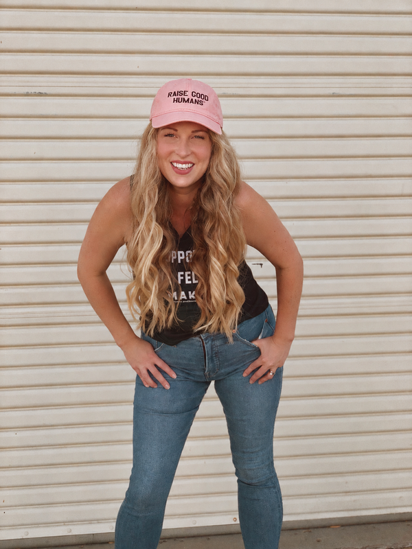 Mom Culture founder Sarah Komers smiling in a pink Raise Good Humans cap.