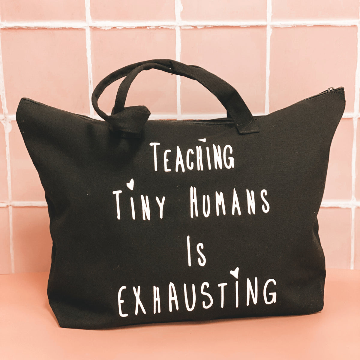 Black tote bag with white “Teaching Tiny Humans Is Exhausting” lettering.