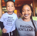 Mother wearing a gray “Raising Gentlemen” T-shirt beside a child.