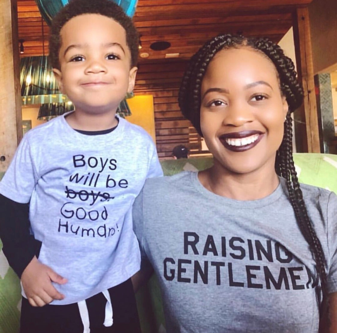 Mother wearing a gray “Raising Gentlemen” T-shirt beside a child.