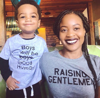 Mother wearing a gray “Raising Gentlemen” T-shirt beside a child.