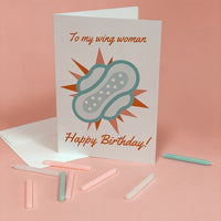 Birthday greeting card reading “To My Wing Woman” with an illustrated winged pad and “Happy Birthday!”