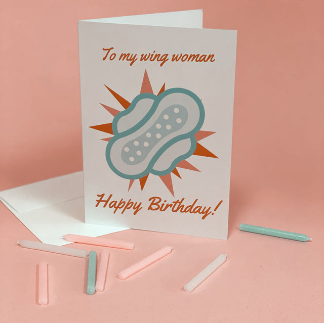 Birthday greeting card reading “To My Wing Woman” with an illustrated winged pad and “Happy Birthday!”